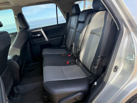 Rear car seats in black & gray, with floor mats, offering a clear ocean view, perfect for journeys often taken with rv rental.