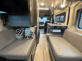 Inside this RV rental, a view down the aisle reveals a compact kitchen, comfy seating, and a TV for mobile travel.