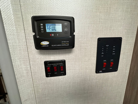 RV rental interior with control panels: Go Power solar charge controller (full battery), heated tank system, and water pump/heater controls.