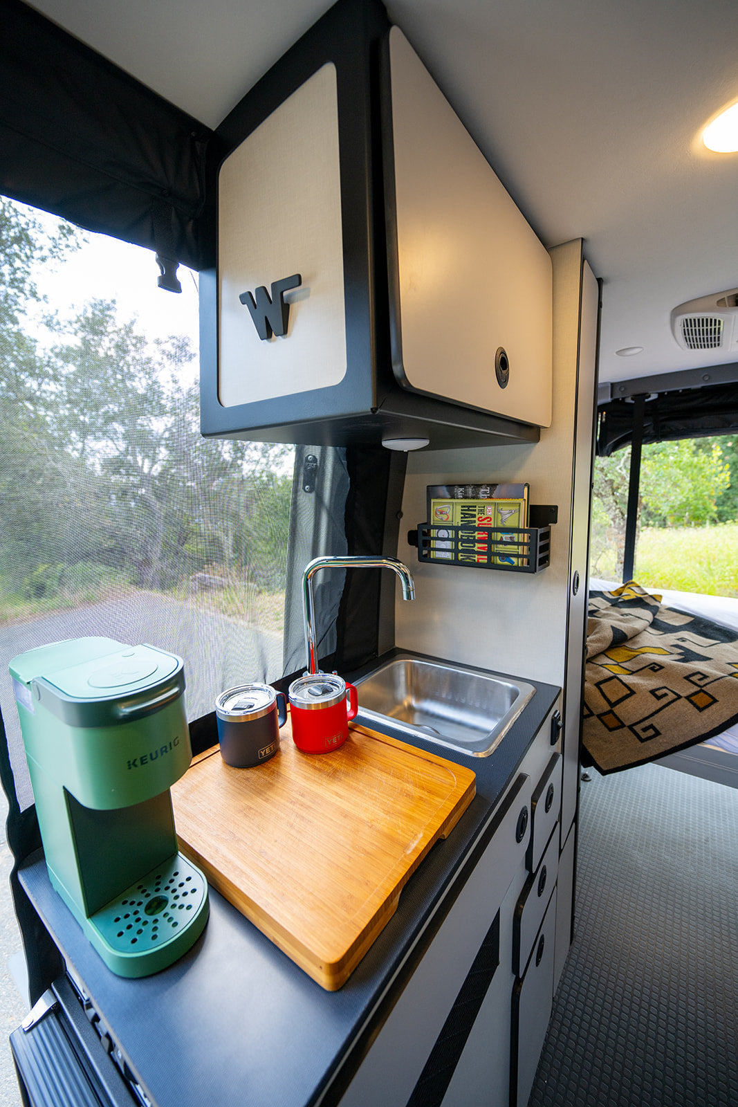 This RV rental features a cozy galley with Keurig, sink, and smart storage, ready for your road trip adventures.