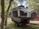 A Rockwood ESP pop-up camper at a shady campsite, fully extended. Perfect for an RV rental adventure.