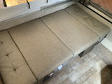 RV rental interior featuring a beige convertible bench seat and bed, with light wood-look and carpet flooring.