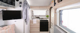 Compact RV rental interior featuring a full kitchenette, living area with TV, and essentials for comfortable travel.