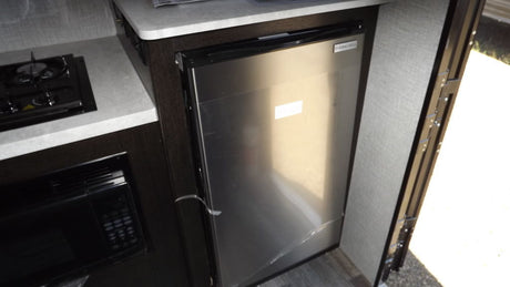 Compact RV rental kitchen featuring a two-burner stove, microwave, and Everchill mini-fridge for convenient travel cooking.