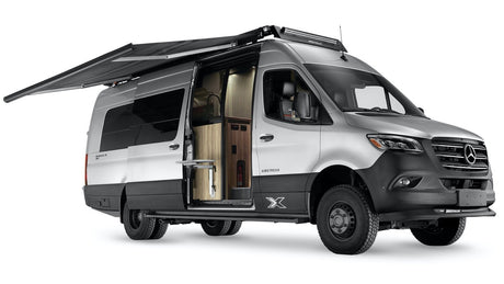 Rugged silver Airstream camper van with extended awning & open door, revealing interior. Ideal for your next rv rental adventure.