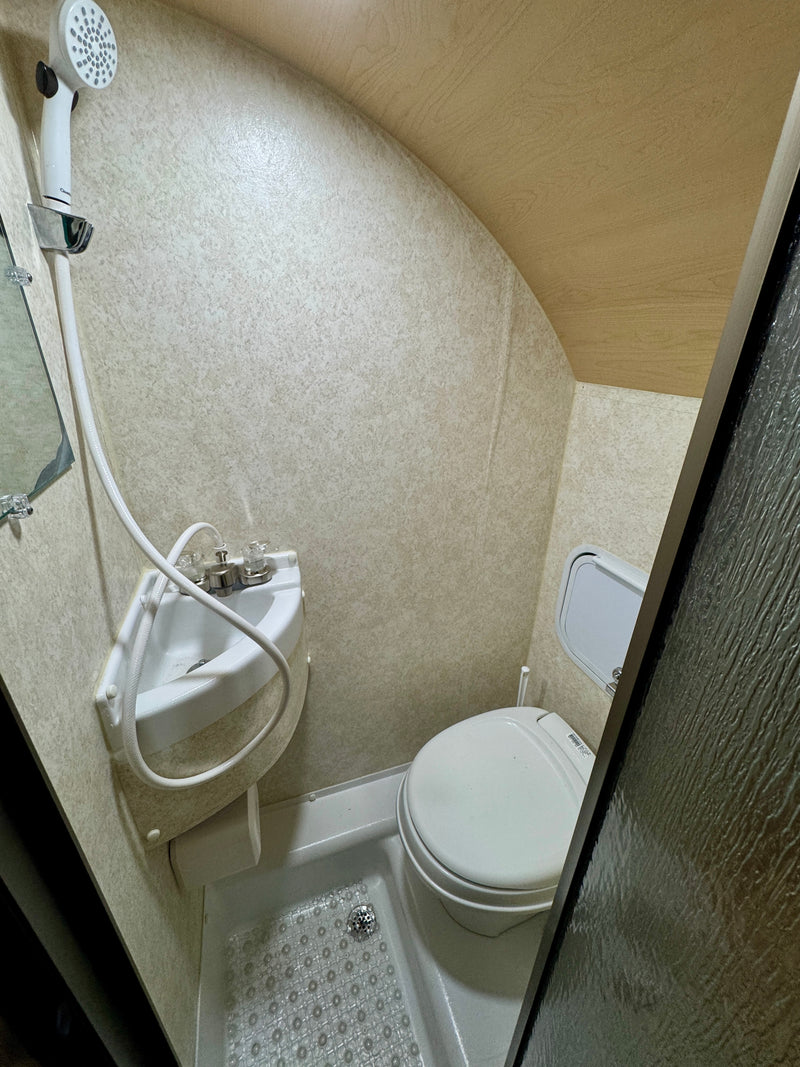 Compact RV rental bathroom showcasing a combined shower, corner sink, and toilet, efficiently designed for small spaces. — photo 11