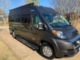 A dark gray Class B camper van, ideal for rv rental, is parked outside on a sunny day.