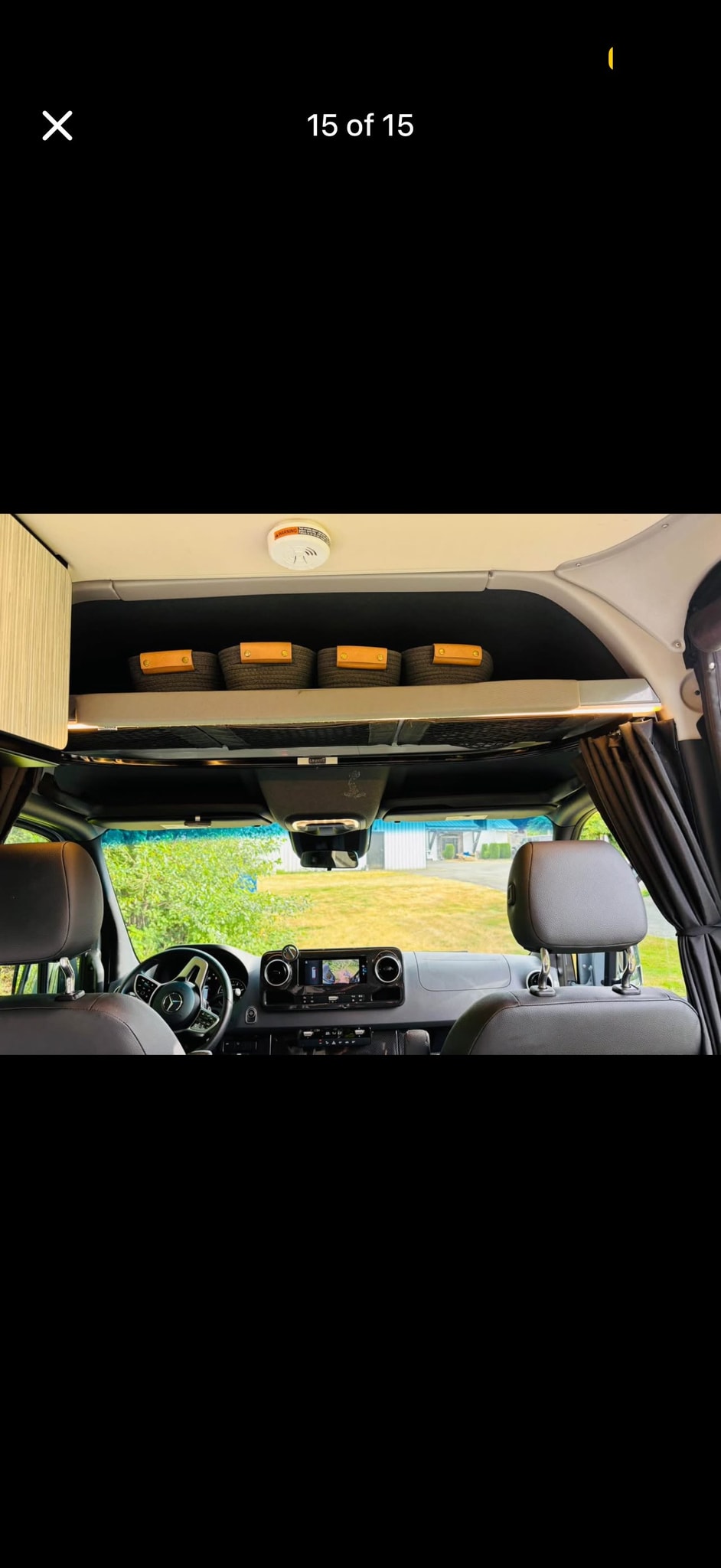 RV rental: Interior view of the driver's cab, dashboard, and overhead storage with woven baskets. Note the ceiling-mounted smoke detector. — photo 9