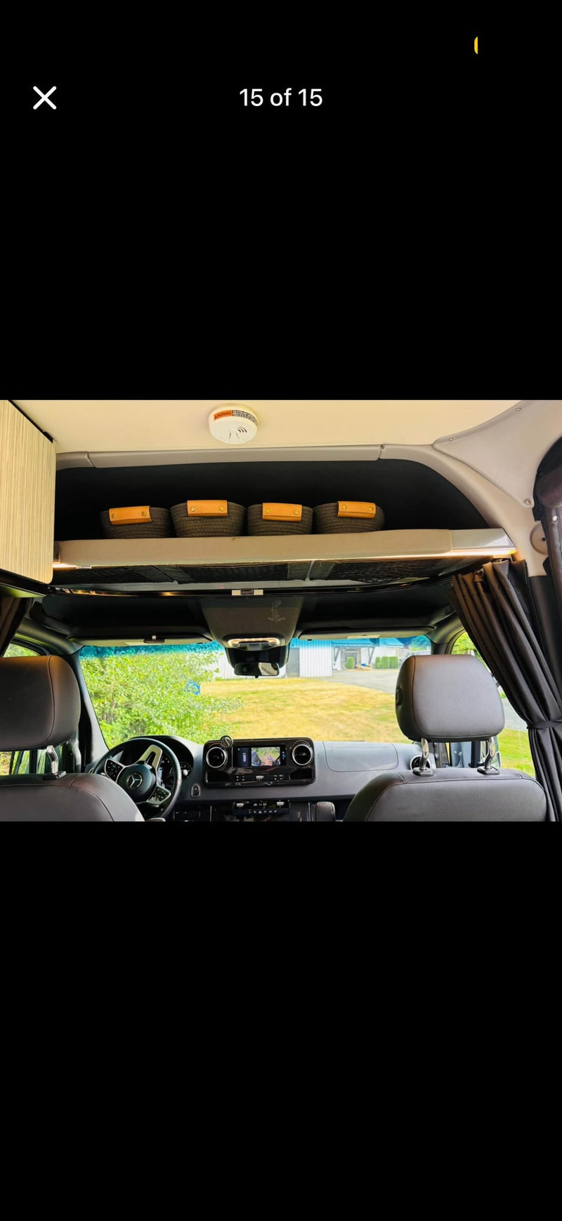 RV rental: Interior view of the driver's cab, dashboard, and overhead storage with woven baskets. Note the ceiling-mounted smoke detector. — photo 9