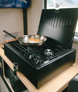 RV rental kitchen: Two sunny-side up eggs sizzling in a pan on a black Dometic gas stove.