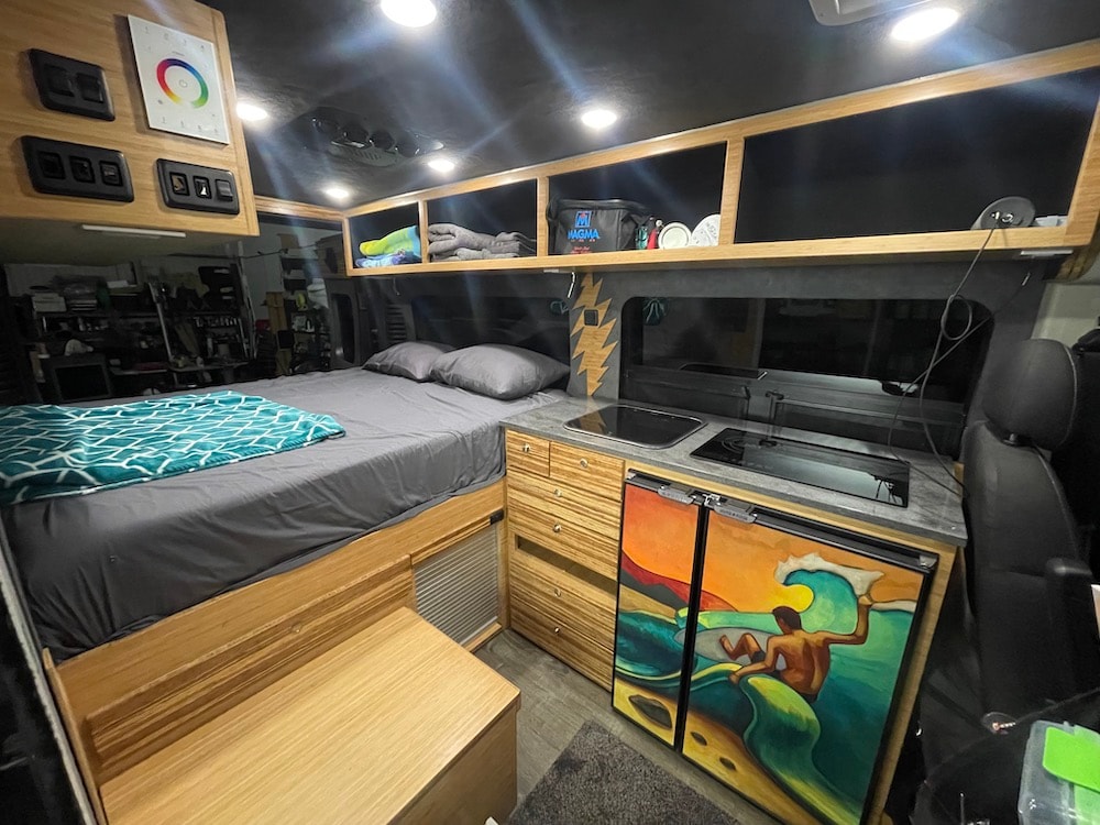  revealing a cozy bed and ocean views. Doors feature vibrant art.|Custom camper van rv rental: enjoy a cozy bed — photo 2
