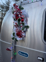 Festive Airstream Bambi RV rental decorated for holidays with candy canes, ornaments, and lights. Perfect for a cozy getaway!