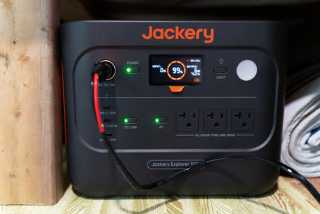 A Jackery Explorer 1000 portable power station, essential for an RV rental or camping trip, shows 99% charge and active outputs.