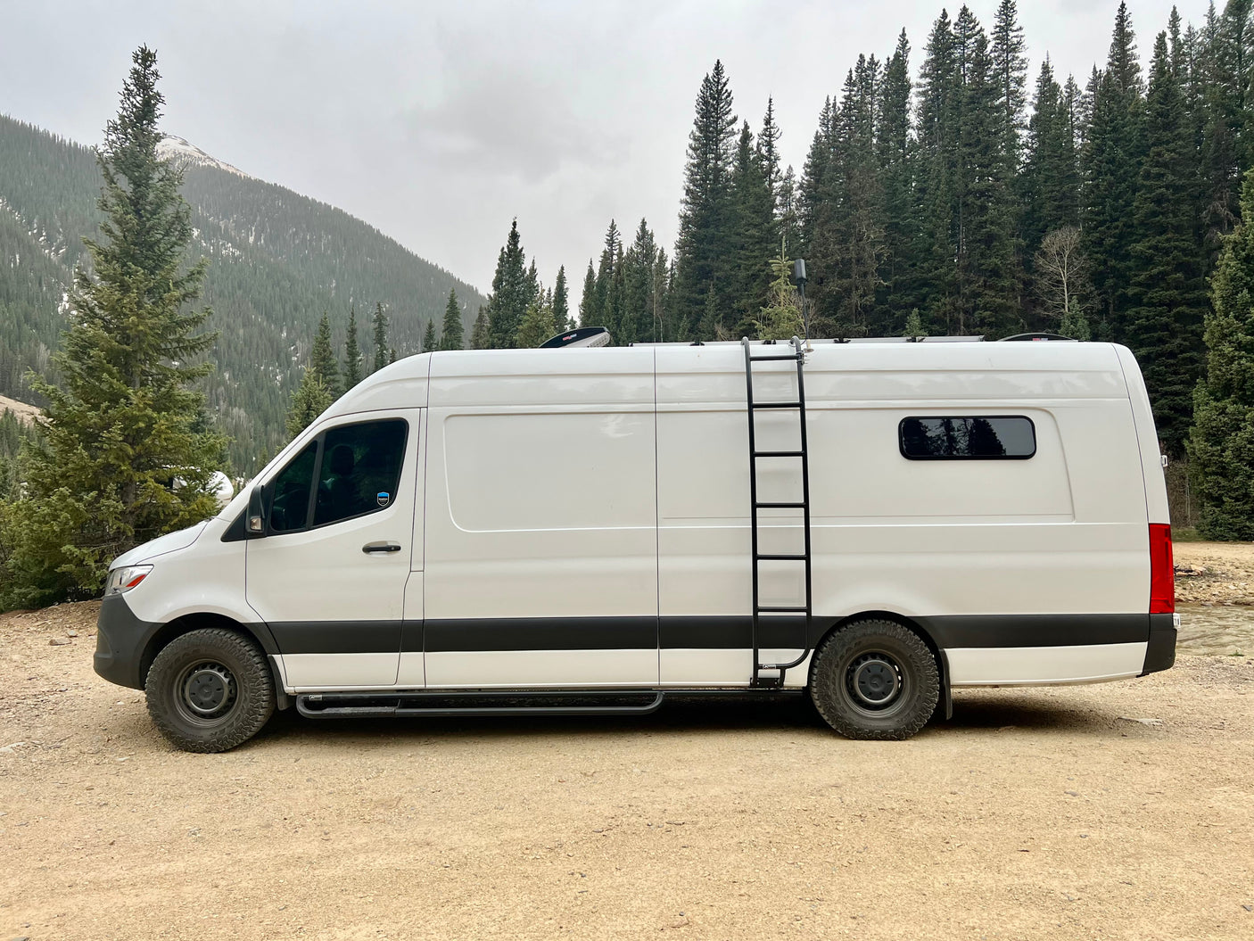 Explore the outdoors in this rugged white Mercedes Sprinter camper van, a great RV rental for mountain adventures.