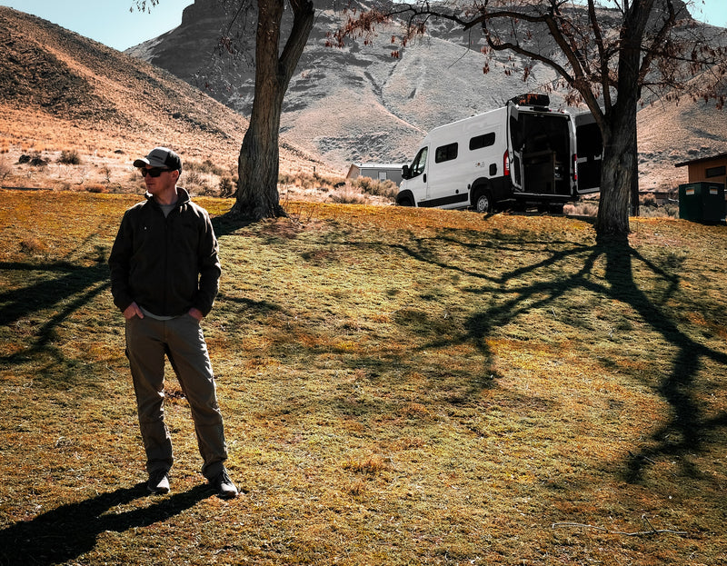 Scenic rv rental adventure. Man stands near his white camper van with open rear doors, parked in a grassy, mountainous landscape. — photo 16