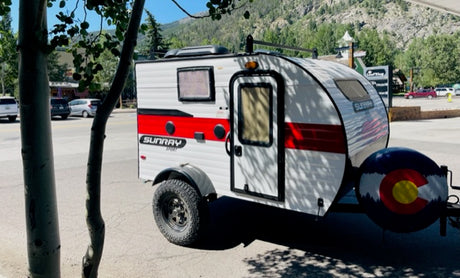 Explore Colorado! This Sunray Sport teardrop camper RV rental with a Colorado flag spare tire cover is perfect for your next adventure.