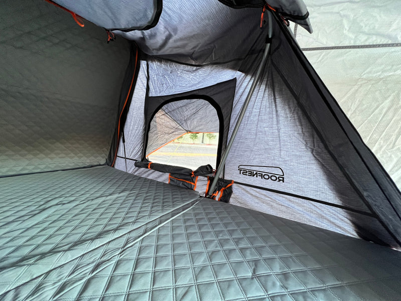 Inside a Roofnest roof-top tent, with quilted bedding & open window views. Ideal for your next rv rental adventure. — photo 8