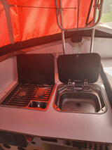 Inside a Dometic-equipped RV rental: compact kitchen with two-burner stove & sink unit. Ideal for camping.