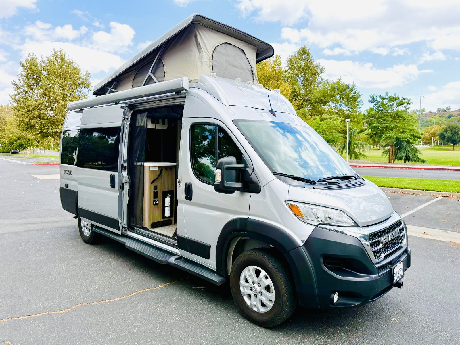 Stylish silver pop-top camper van rv rental, parked with its side door open, revealing a peek at the cozy interior.