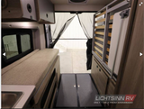 RV rental interior: a versatile space with a bed/lounge, fold-up bed frame, sink, and mesh rear screen for camping.