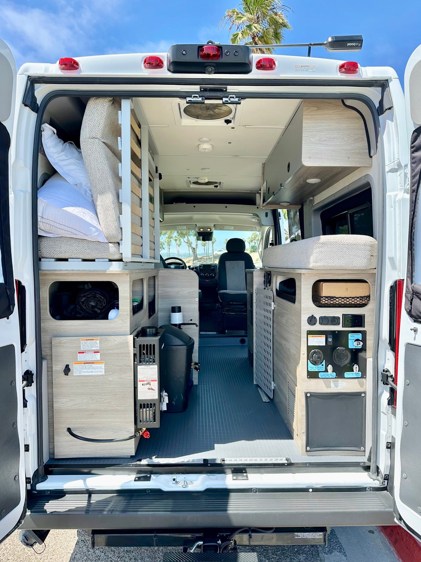 View from the rear of an **rv rental** camper van, showcasing custom interior layout with beds, storage, and water system. — photo 15