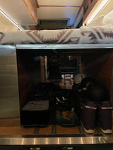 RV rental interior: Under-bed storage packed with snowboards, helmets, and boots. Ready for adventure!