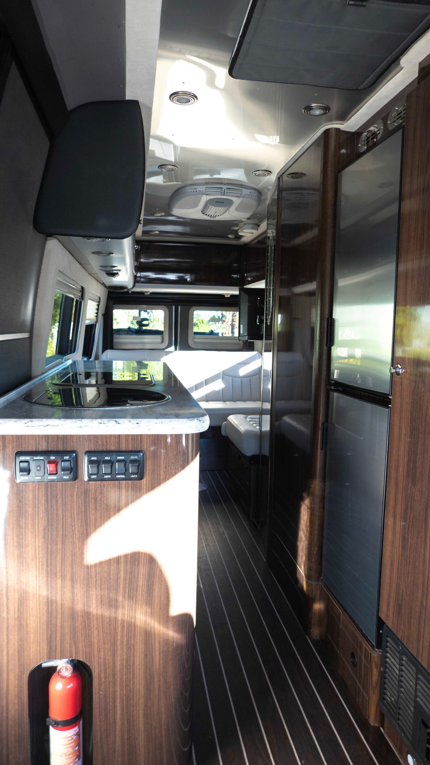 This rv rental's modern interior features a compact kitchen with a sink/cooktop, fridge, and comfortable rear seating.