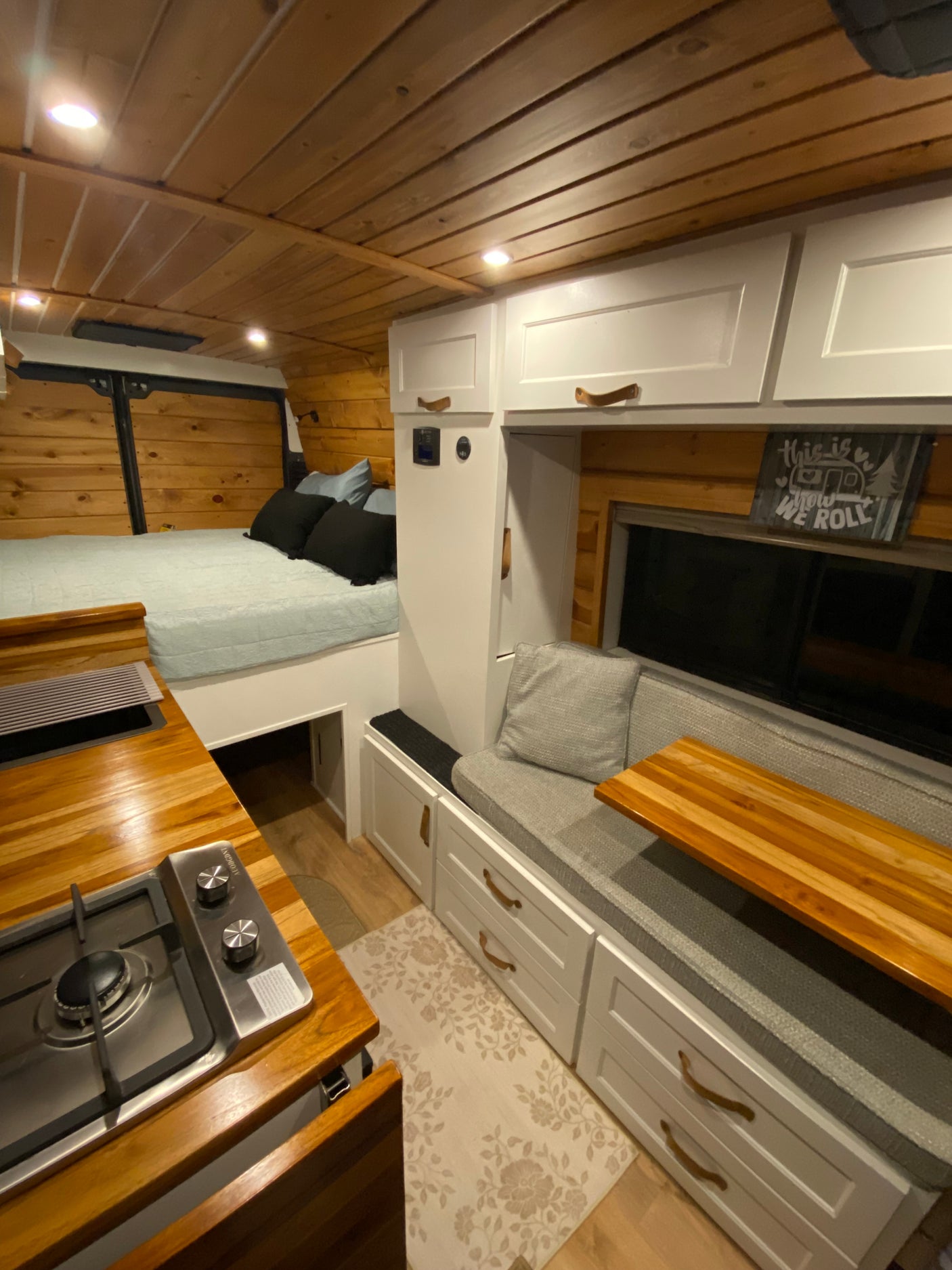 Inside a stylish RV rental: wood-paneled walls, a cozy bed, compact kitchen, and versatile seating.