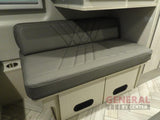 Comfortable RV rental interior: Gray upholstered dinette bench with under-seat storage & cup holder.
