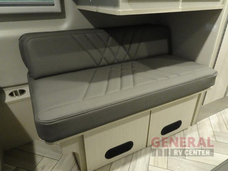 Comfortable RV rental interior: Gray upholstered dinette bench with under-seat storage & cup holder.