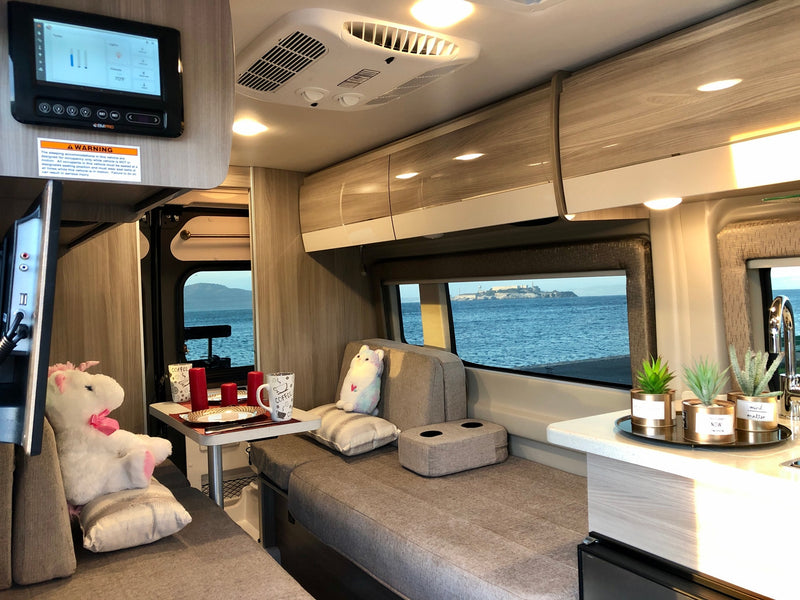 Inside an rv rental: a cozy living space with dining area, plush friends, and a stunning view of Alcatraz Island over the water. — photo 12