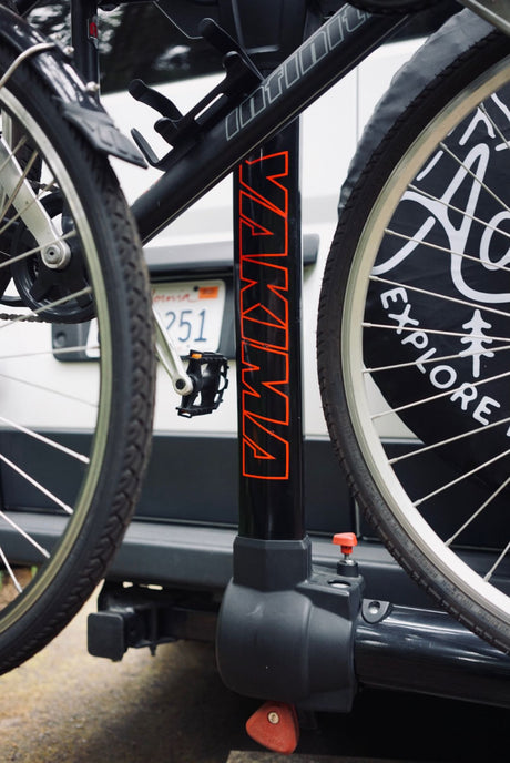 Bike rack on an RV rental with two bikes ready for adventure. Features Yakima branding & 'Explore' graphic.