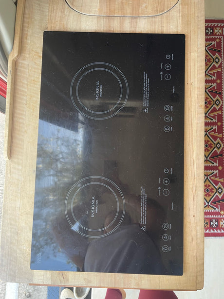 Black Insignia portable induction cooktop on a wood counter, great for RV rental cooking.