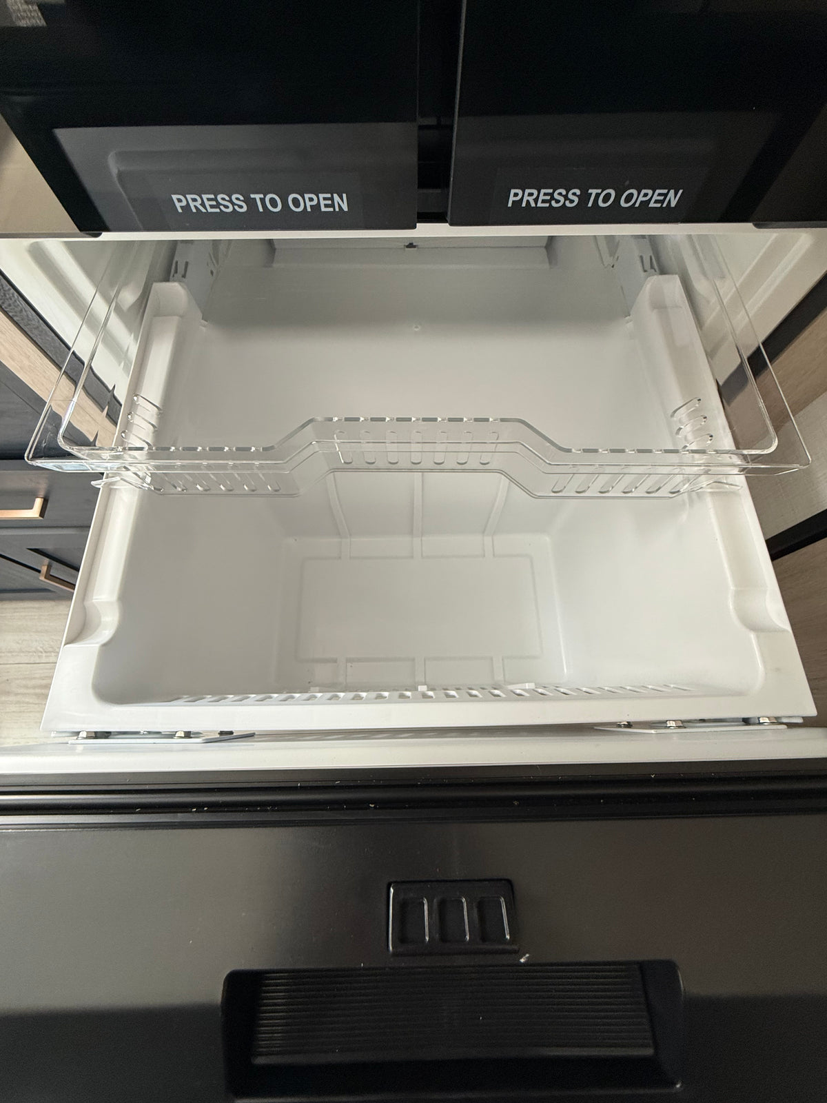 Inside an rv rental appliance: a clean, empty white pull-out drawer with a clear shelf, below two "PRESS TO OPEN" compartments. — photo 7