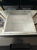 Inside an rv rental appliance: a clean, empty white pull-out drawer with a clear shelf, below two "PRESS TO OPEN" compartments.