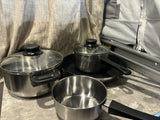 RV rental kitchenware: stainless steel pots, pans, and lids, ready for camping meals in a mobile kitchen.