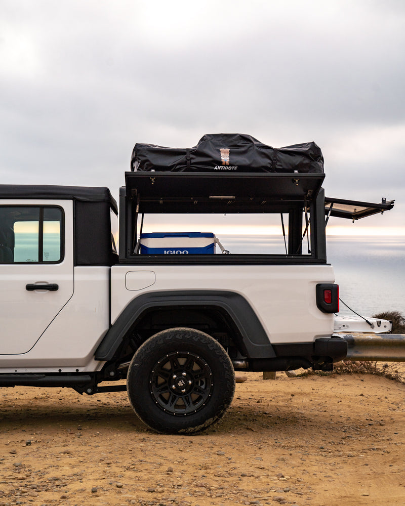White Jeep Gladiator pickup with truck bed cap, rooftop tent, and cooler, ideal for your next RV rental overlanding trip. — photo 7