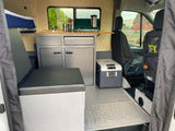 Inside an RV rental: a compact camper van conversion with a kitchen, bed, fridge, and ample storage for your travels.