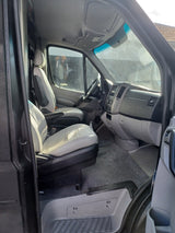 Angled view of an RV rental's cab interior: light gray driver & passenger seats, dashboard, and steering wheel are visible.