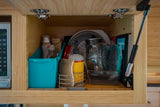 Inside a light bamboo RV rental cabinet: neatly organized kitchen and cleaning essentials like soap, sponge, and dishes.