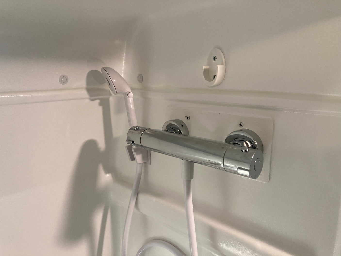 Clean, compact shower setup in an RV rental, featuring a modern chrome mixer & handheld shower. Essential amenities for travel.