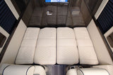Luxury RV rental interior with comfortable quilted bedding laid out, converting from seating for a spacious sleeping area.