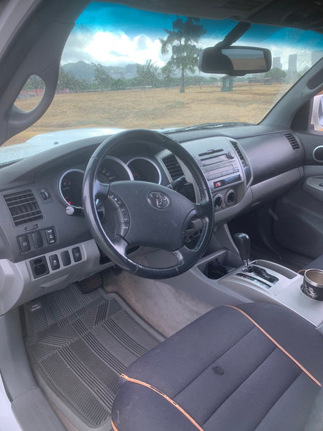  a cozy quilted mattress awaits with a stunning view of Hawaii's Diamond Head.|White Toyota Tacoma pickup with covered camping gear in bed. Explore versatile travel options from an RV rental service.|Interior of a Toyota vehicle