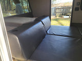 This RV rental interior features a convertible leatherette sofa/bed and dinette, with serene outdoor views.