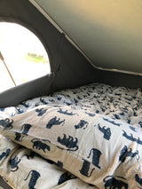 Cozy RV rental interior: A comfortable bed with distinctive white and blue tiger-patterned bedding, ready for adventure.