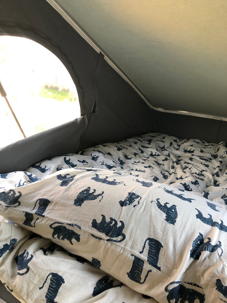 Cozy RV rental interior: A comfortable bed with distinctive white and blue tiger-patterned bedding, ready for adventure.