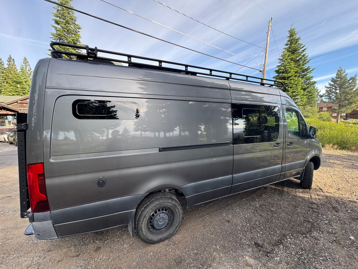  alongside an open mini-fridge for space-saving.|Gray RV rental van on a dirt road — photo 5