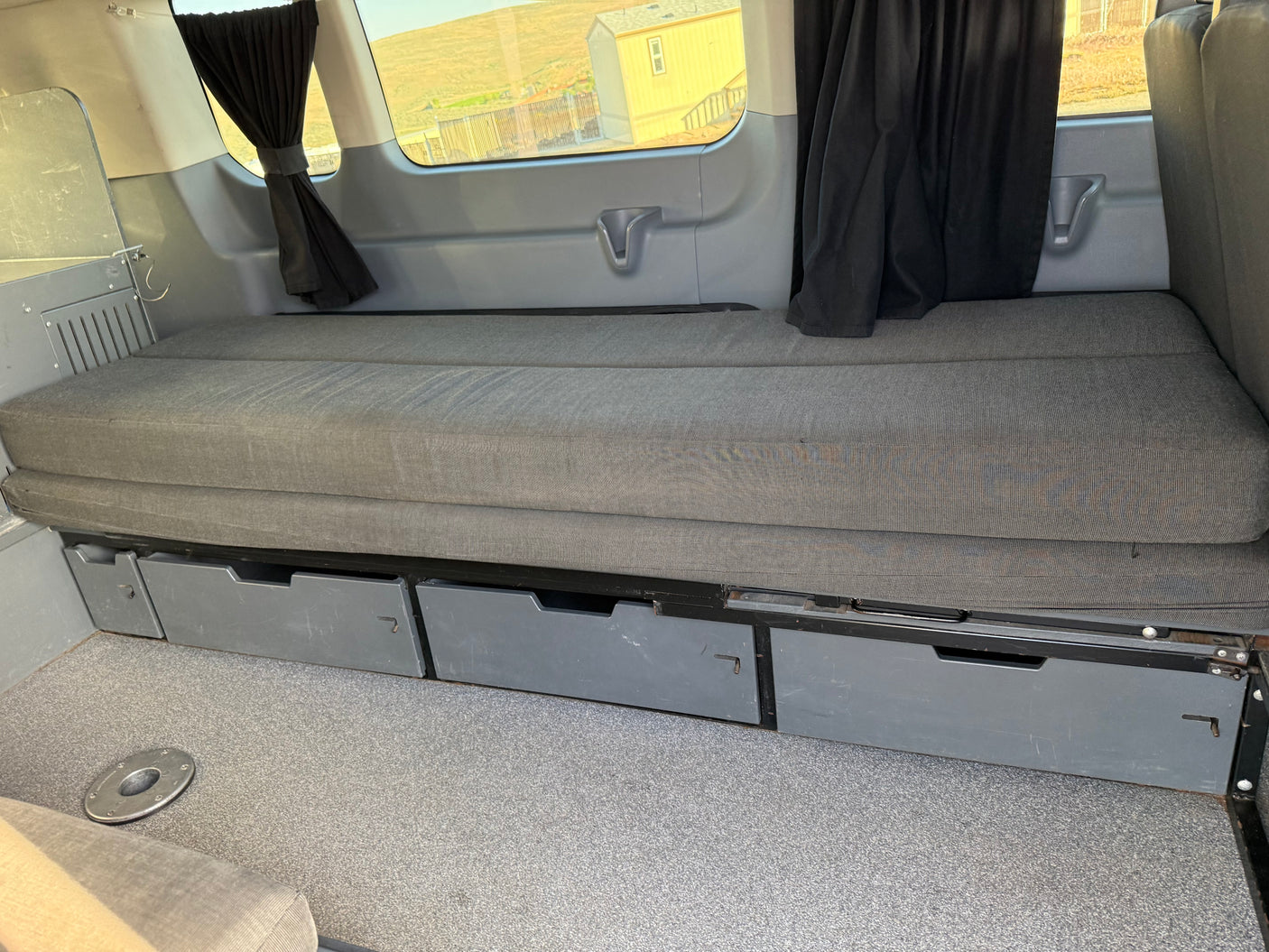 This RV rental offers a cozy, convertible bed with convenient under-bed storage drawers and window curtains for privacy.