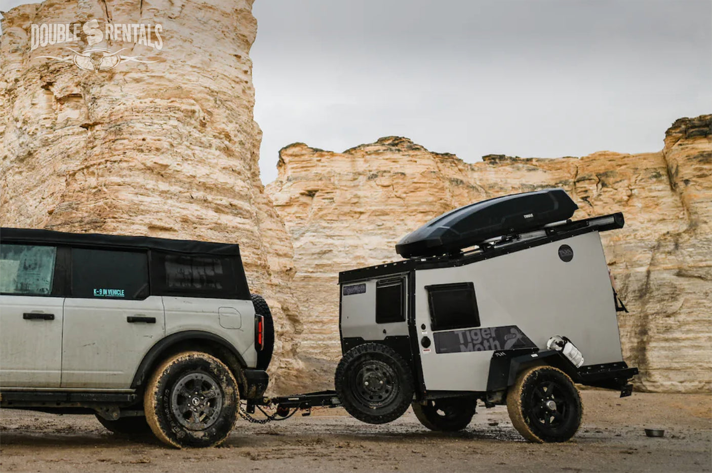 Experience off-grid camping with an RV rental from Double S Rentals: A rugged SUV and Tiger Moth camper against stunning rock formations.