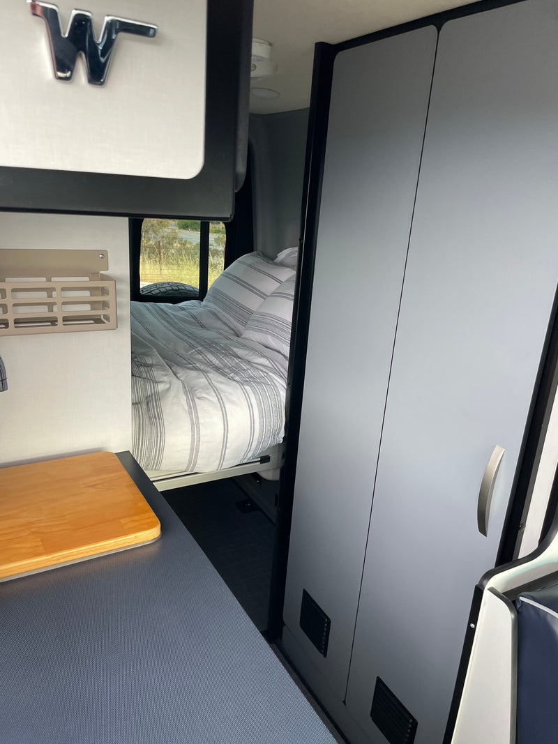 Winnebago rv rental interior: a comfy bed, kitchenette with wood counter, and sleek storage cabinets. — photo 8